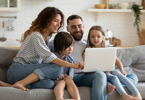 Hombre sonriendo junto a su familia navegando en internet Hombre sonriendo junto a su familia navegando en internet